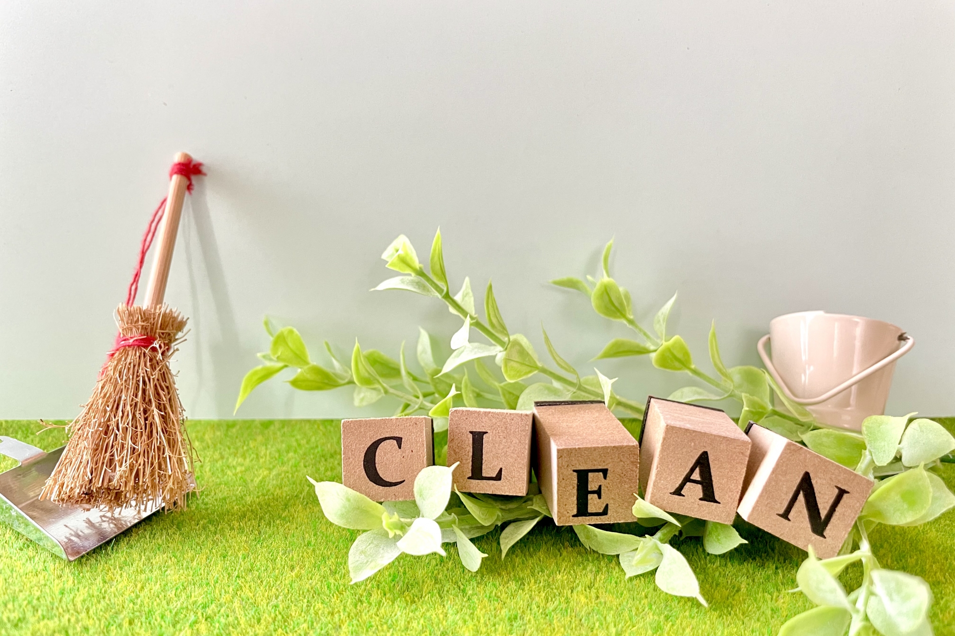 ほうきとグリーン、CLEANの文字ブロックが並ぶ明るい写真。掃除で家全体を整えるイメージ