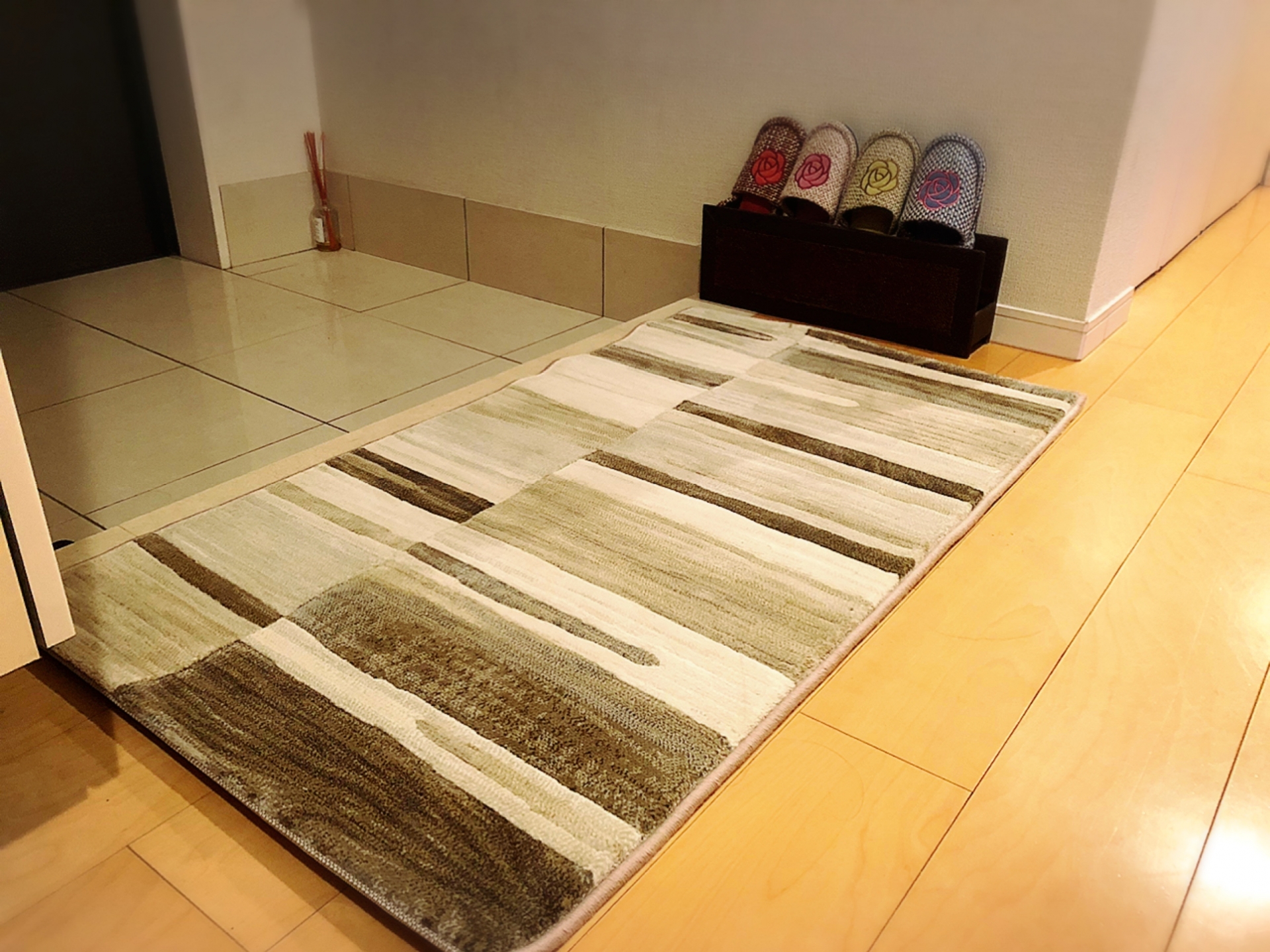 玄関に敷かれた明るい色のマットと観葉植物の写真(金運アップの風水インテリア)