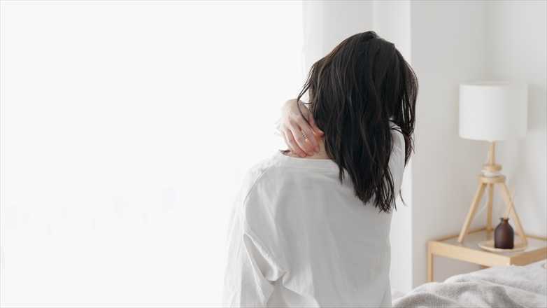 首元を手でかく女性の後ろ姿。秋花粉による肌荒れや不調をイメージした写真