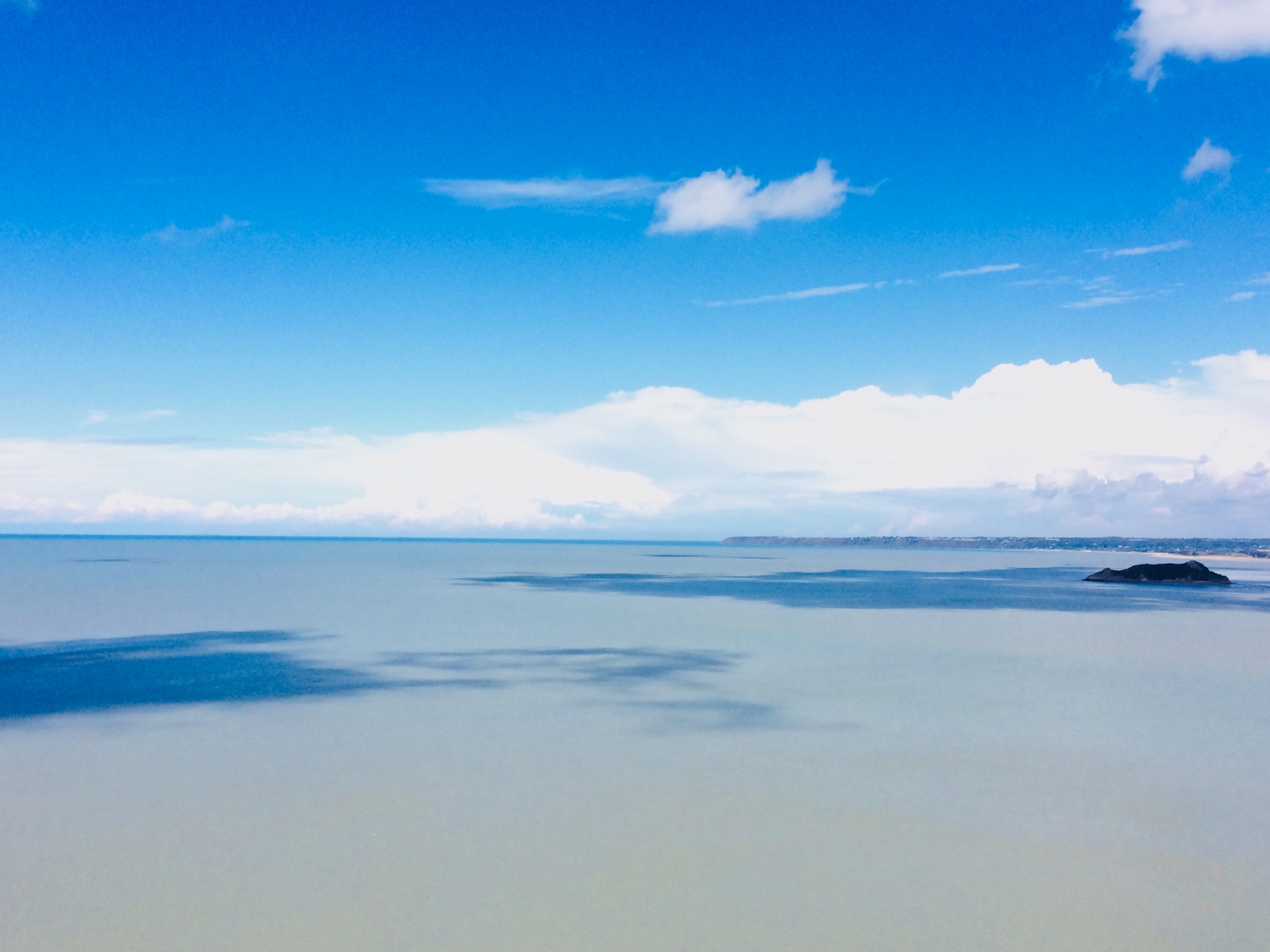淡い青空と静かな海が広がる穏やかな風景。頑張りすぎた心をふっとゆるめるイメージ