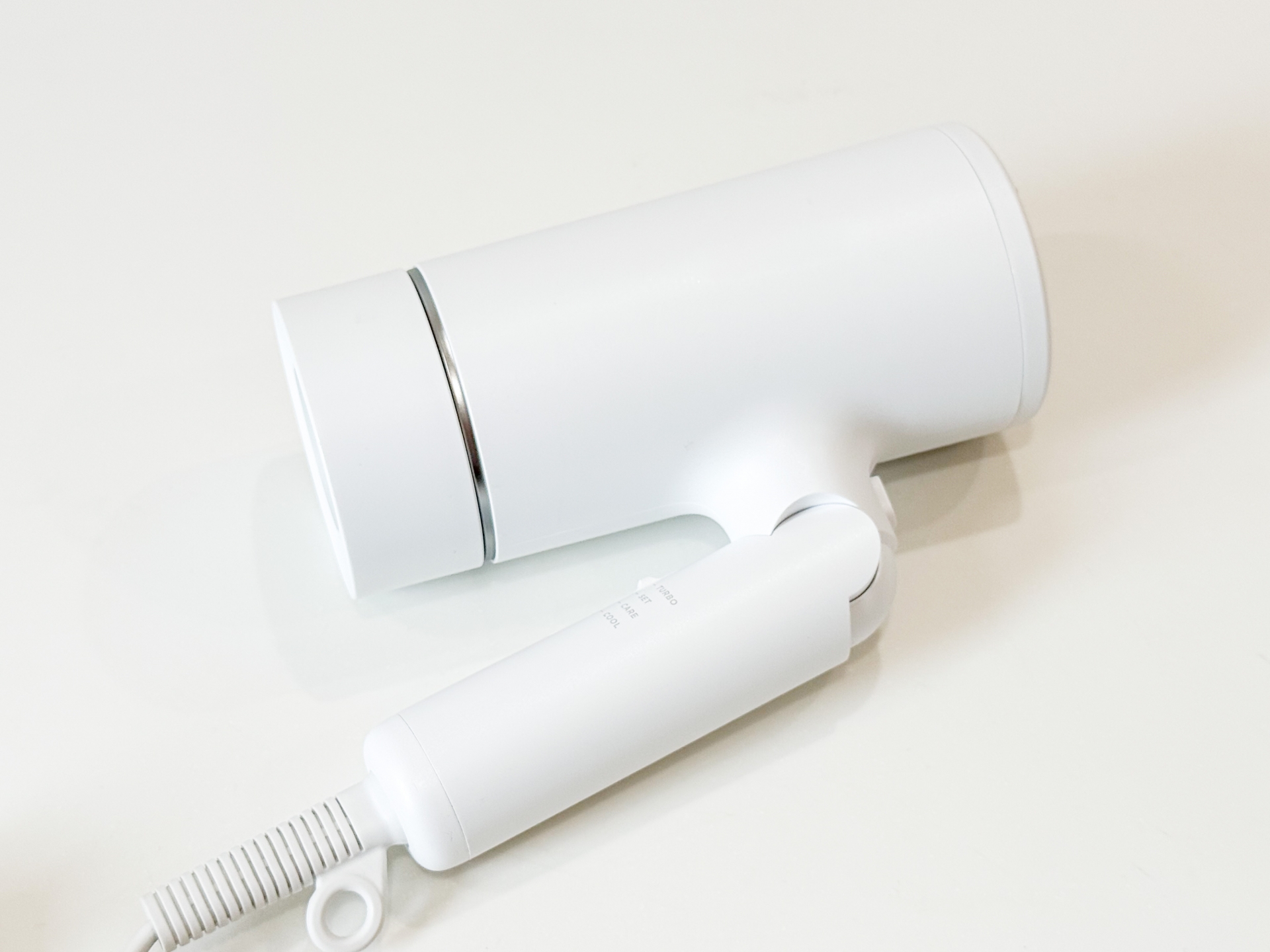 白いドライヤーが置かれた明るい背景。生活の変化やリセットをイメージした写真