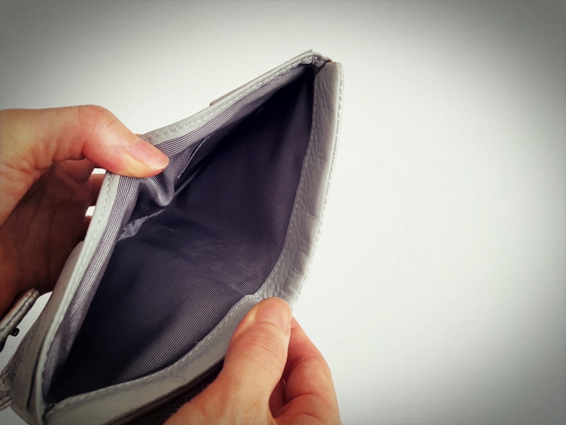 中身が少ない財布を手に持って見直している様子の写真