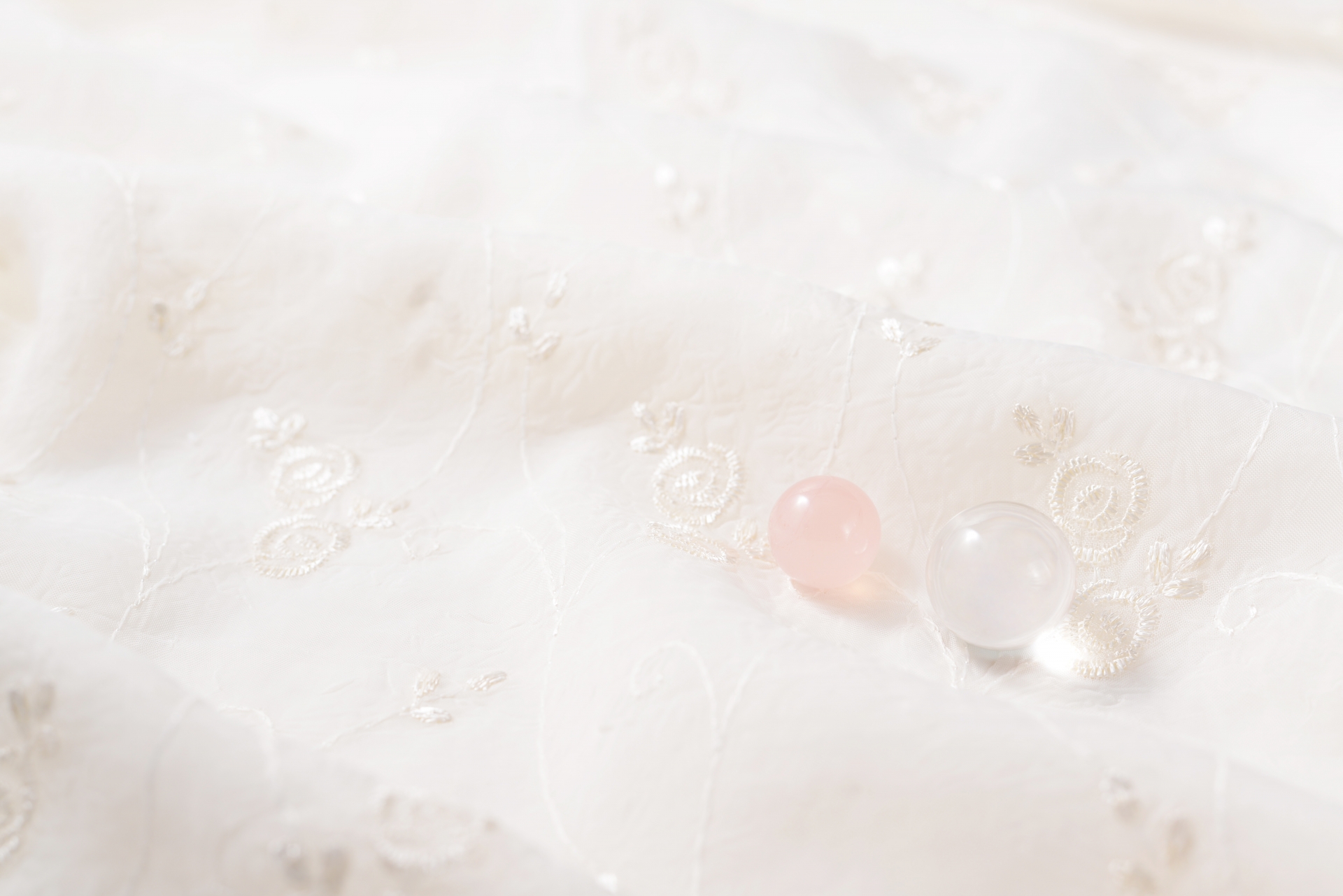 白い布の上に淡い色の石が置かれた、静かで落ち着いた雰囲気の背景写真